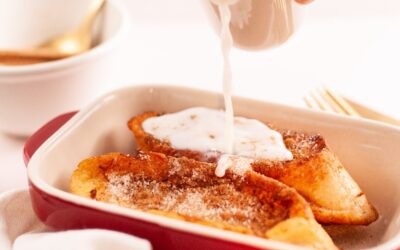 bandeja de cocina con dos torras y una mano con una jarrita de leche vertiendo la leche sobre las torradas