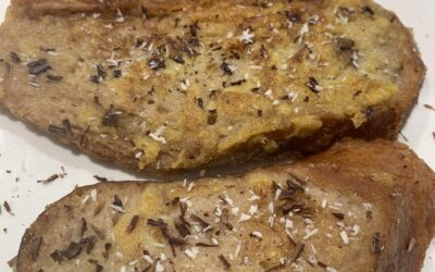 tres torrijas veganas sobre una bandeja blanca llevan espolvoreado chocolate y coco